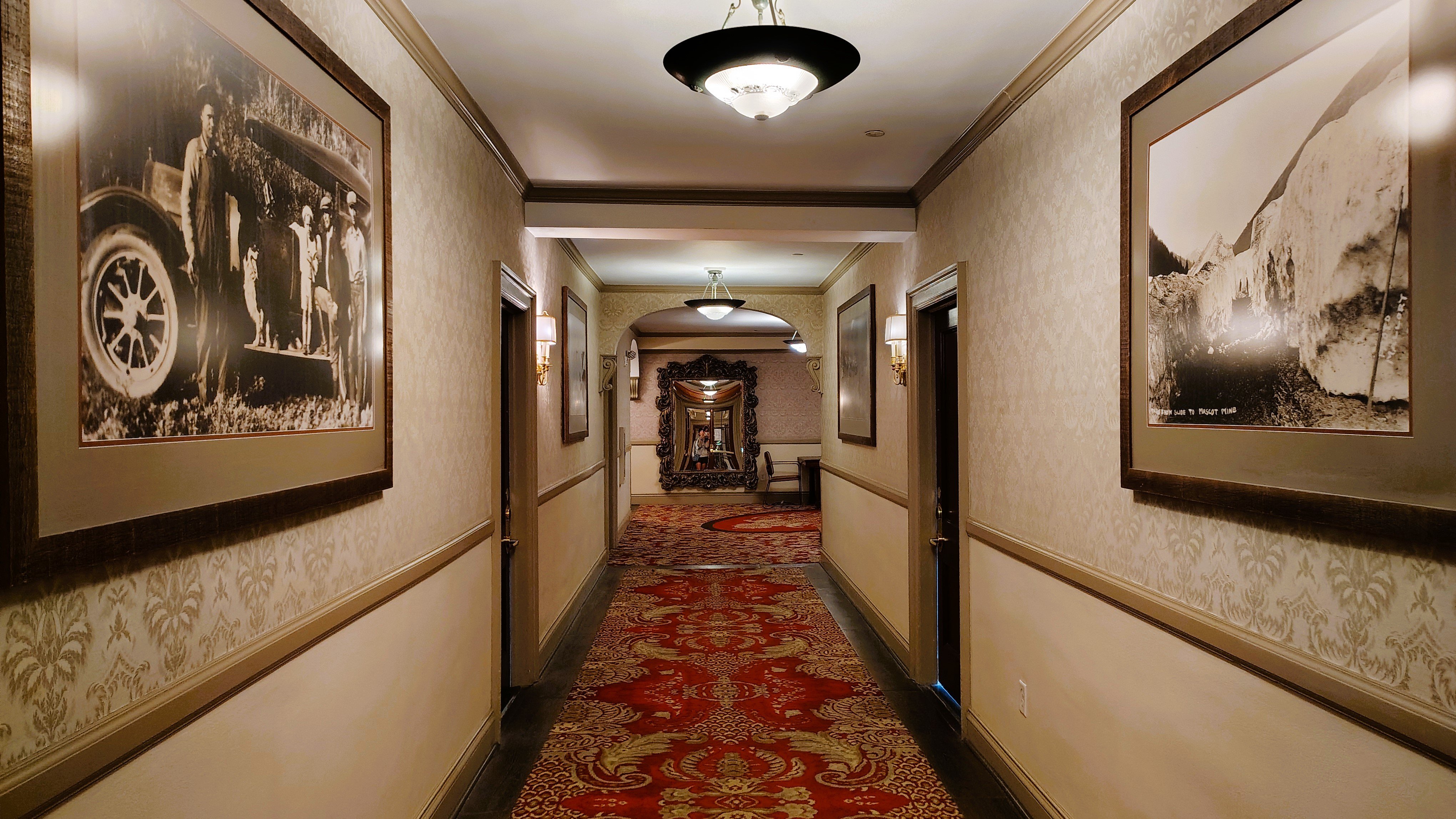 The hallways at The Stanley Hotel have dark red carpeting, dark wood trim and cream wallpaper. There's a mirror at the end of the hall.